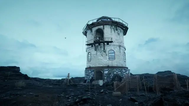 A white stone lighthouse on a black rocky shore under a grey sky