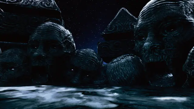 Giant carved stone faces at the water's edge at night